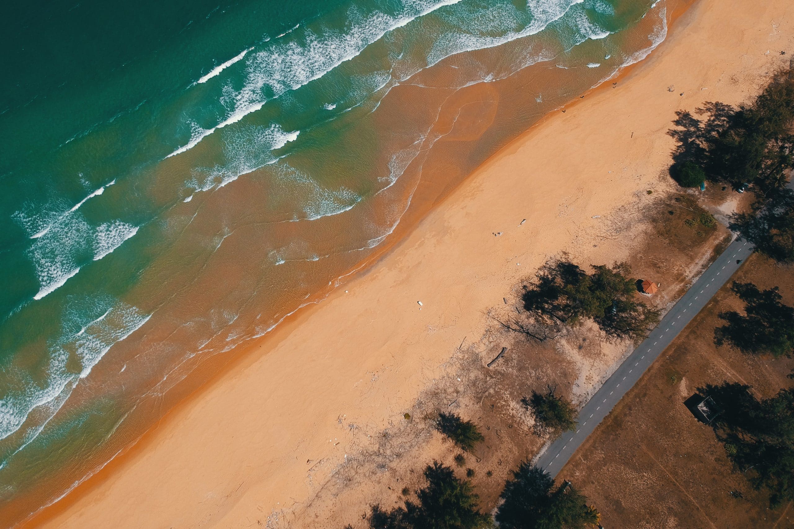 Top down view of a sandy shore with clear blue waters